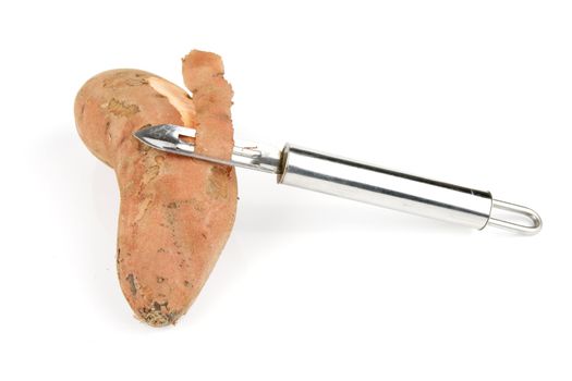 Sweet Potato cut in half with a silver potato peeler on a reflective white background
