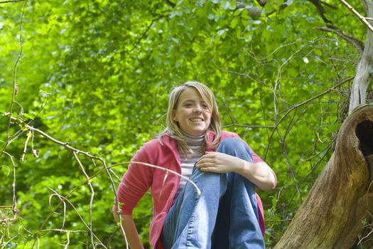 Teenage girl smiling from her perch in a tree.