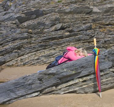 Teenage girl relaxes in the sunshine,with an umberella cover at hand.