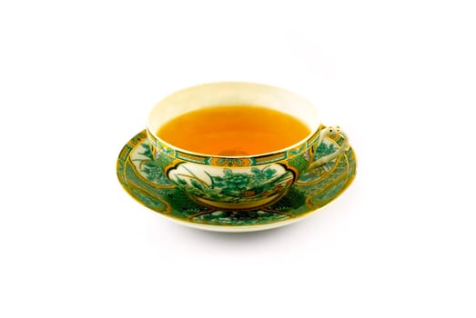 The beautiful cup of tea on a plate is photographed close up on a white background