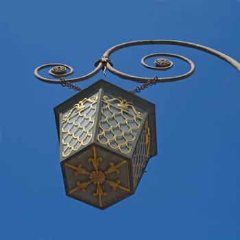 A photo of an old street lamppost against blue sky
