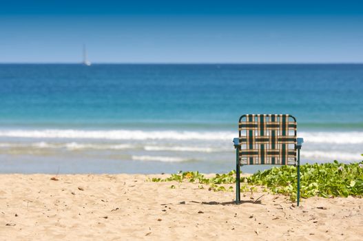 Chair sits on an inviting tropical shore.