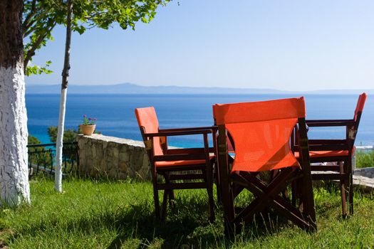 Red chairs in open-air greek cafe overlooking the sea gulf