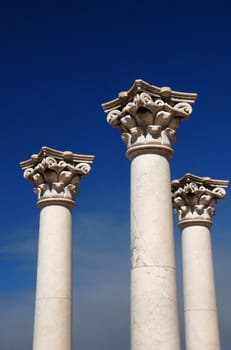 Three ancient greek pillars against a blue sky