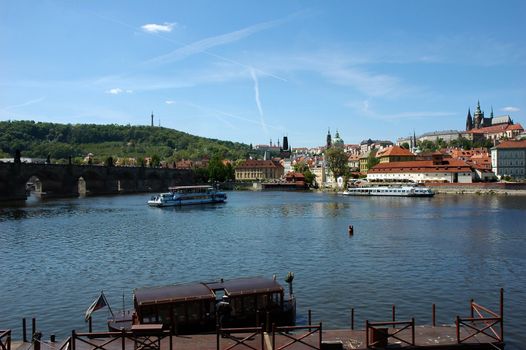 Scenery of Prague with Charles bridge, cathedral, castle and ships.