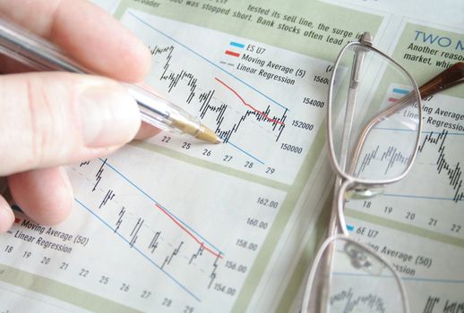 Hand with pen marking stock charts