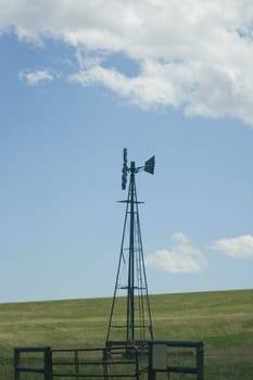 Windmill set against a blue sky and cloud background.
