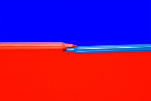 Red and blue felt-tip pens lay on a color background