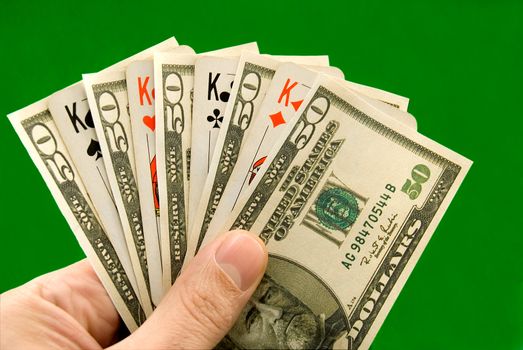 Playing cards and fifty - dollar denominations on a green background