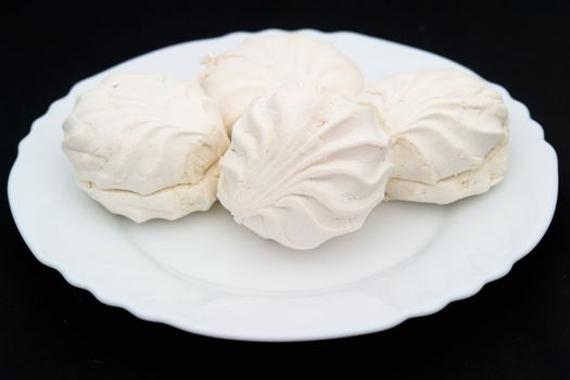 Marshmallow. Souffle on a white plate on black.