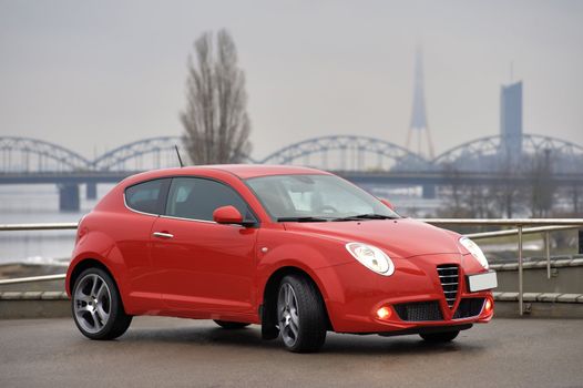 Red car parked on the background of the bridge, Riga, Latvia