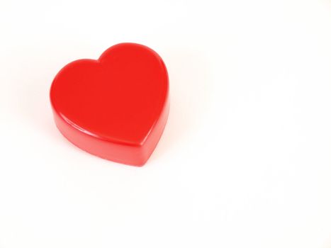 A plastic red heart shape on a white background with room for text.