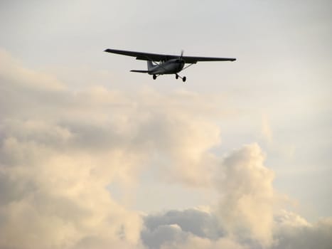 Propeller Airplane Clouds and Sky captures a small plane out of the clouds on final approach to land. 