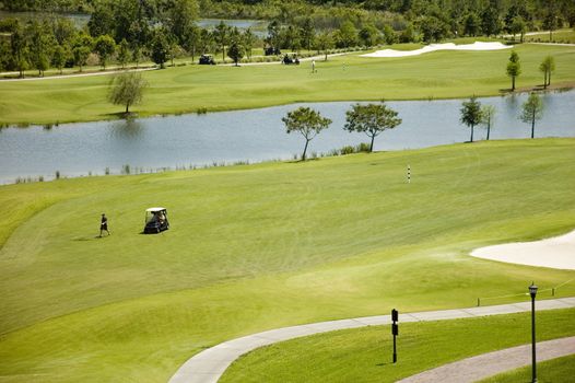 A well-tended golf green with sand traps, golf carts and players in Florida.