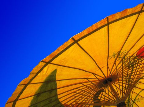 Yellow Asian or Oriental parasol against a clear deep blue sky