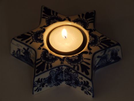 Small candle in a decorative porcelain stand.