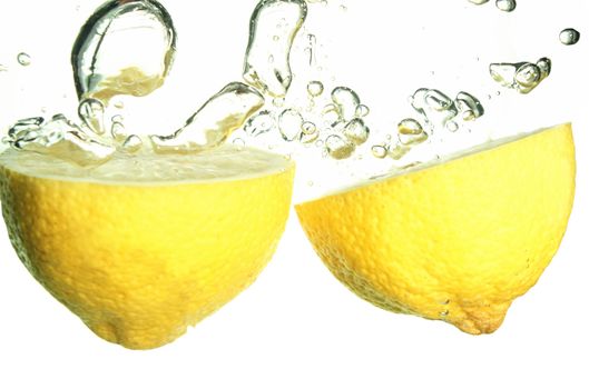 Splash of yellow lemon to water with bubbles of air