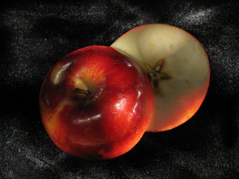 bright red apple cut hand-and-half on black velvet