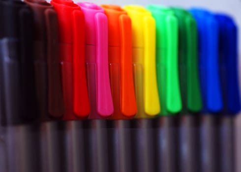 An abstract photograph of a row of colourful pen caps, blurring artistically