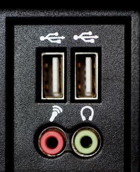 A close-up photograph of a computer's USB hub and the sockets for microphone and speakers