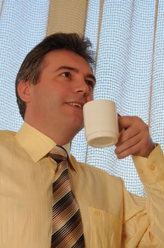 man in a tie on a background a window with a white cup