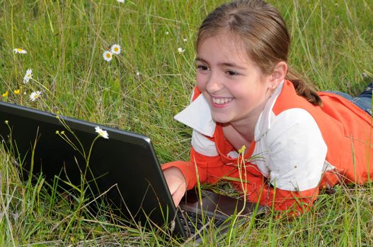 girl lies on a grass on to the meadow and works with a notebook
