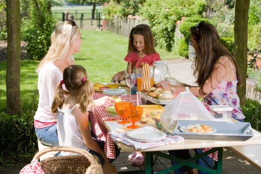 Mothers and their daughters having a picnic outdoors on a summer day