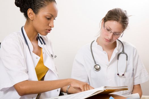 Two medical students looking through the books together