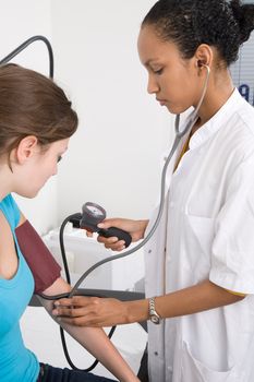 Doctor measuring the bloodpressure of her patient and listening with the stethoscope