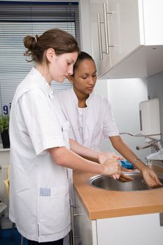 Two young medical students thoroughly washing their hands