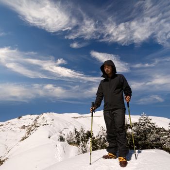 Mountaineer stand on snow mountain peak with trekking pole.