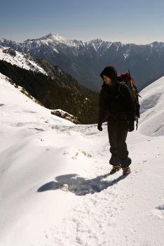 Backpacker on snow mountain path in winter.