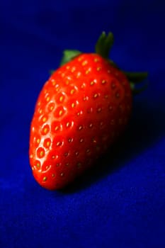 Brightly red strawberry on blue background.