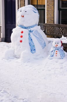 Funny Snowman and son in front of house in the street  - vertical image