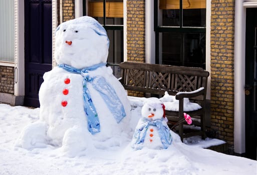 Funny Snowman and son in front of house in the street - horizontal image