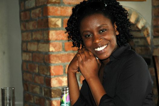 african girl siting in the restaurant, looking and smiling at the camera