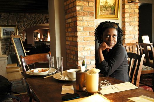 african girl siting in the restaurant, looking and smiling at the camera