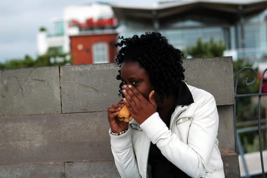african young girl eatting a French bread covering her face