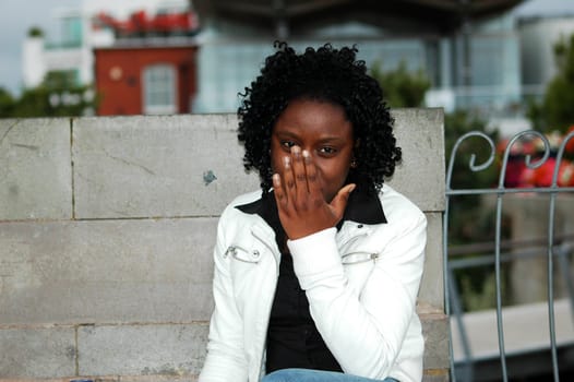 african young girl smiling at the camera, but covering her face