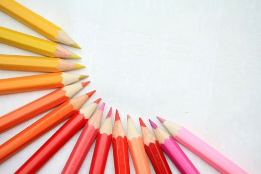 A collection of red, yellow, orange and pink colorpencils, brand new and sharp