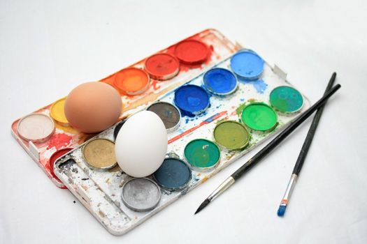 Different colors of paint, brushes and fresh eggs to make traditional easter decorations