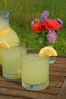 two glasses of lemonade and a bouquet of flowers outside.