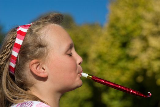 a young girl outside with party blower