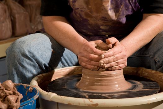 Hands forming clay pot on pottery wheel