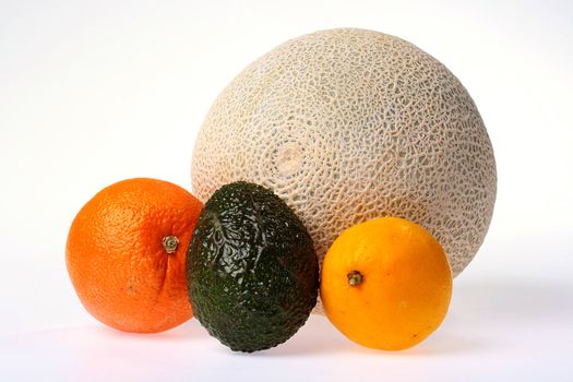 Four different fruit on a white background: a melon, an orange, a lemon and avocado.