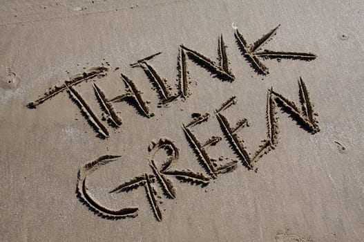 The words "Think Green" are carved into a sandy beach