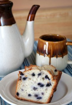 plate of blueberry cake with coffee cup and coffee pot.
