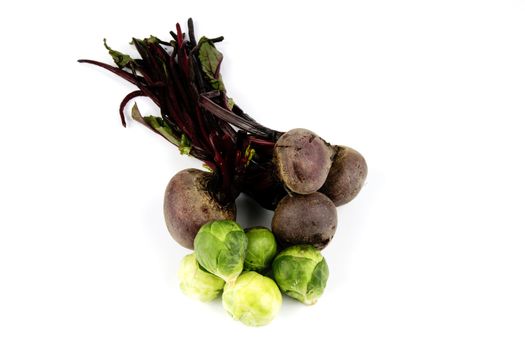 Bunch of raw red beetroot with a pile of small green sprouts on a reflective white background