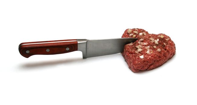Knife cuts heart made of minced meat