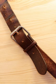 Closeup of old leather belt lying on wooden background with copy space